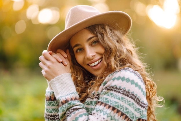 Mujer feliz con elegante suéter y sombrero al aire libre en el parque de otoño en cuadros La mujer disfruta de la naturaleza otoñal