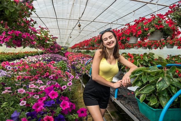 Mujer feliz elige flores en invernadero. Botánica
