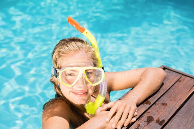 Mujer feliz con equipo de snorkel apoyado en el lado de la piscina