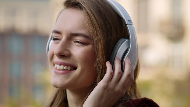 Mujer feliz escuchando música con auriculares al aire libre Chica sonriente bailando en la calle