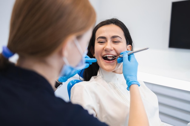 Mujer feliz en el examen preventivo en el dentista Paciente femenino en clínica dental