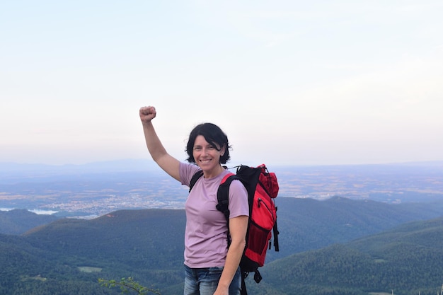 Mujer feliz excursionista para llegar a la cima