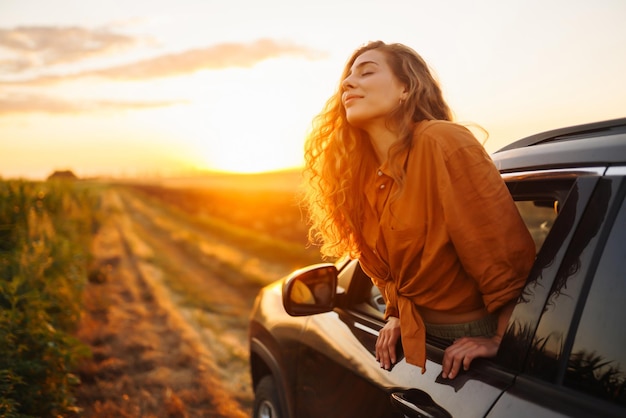 Mujer feliz extiende los brazos mientras se asoma por la ventana del coche Estilo de vida viajes turismo naturaleza