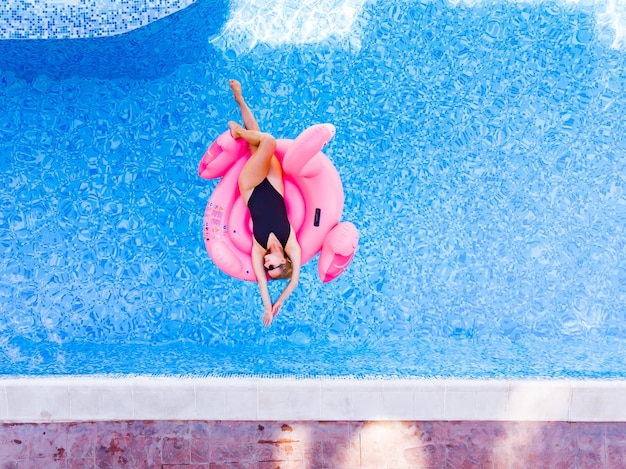 Mujer feliz en flotador de piscina flamingo en piscina, vista aérea de drone