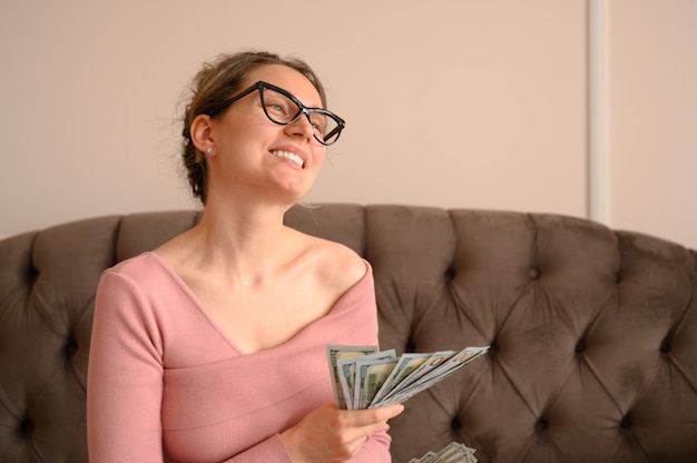 Mujer feliz con gafas negras mostrando dinero