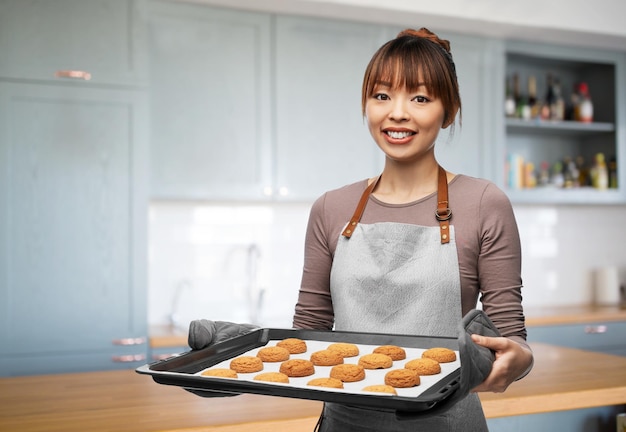 mujer feliz con galletas en la bandeja del horno en la cocina