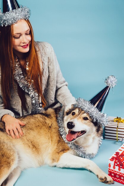 Mujer feliz con gorro festivo se sienta junto a perro grande