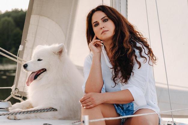 Una mujer feliz con un gran perro blanco en un yate blanco en el mar