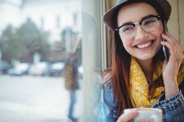 Mujer feliz hablando por celular en el café