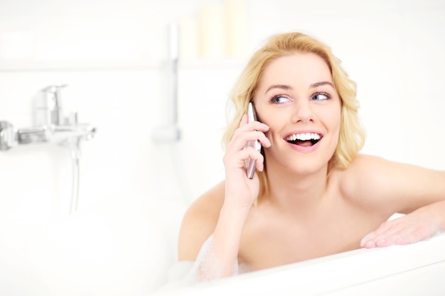 mujer feliz hablando por teléfono al tomar un baño