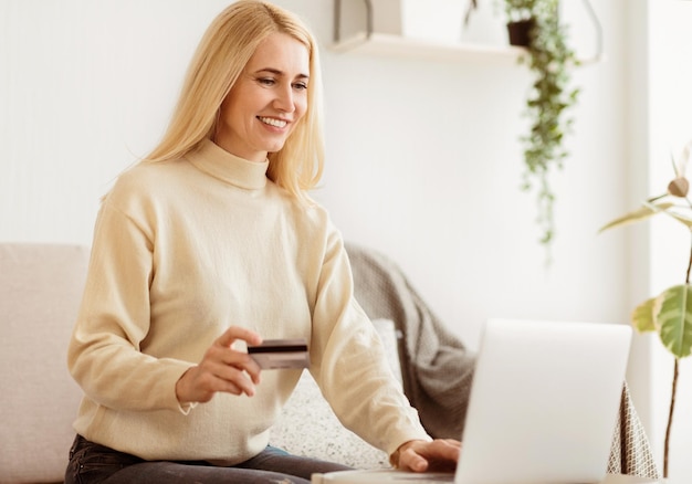 Mujer feliz haciendo compras en línea en casa usando el espacio libre de la computadora portátil