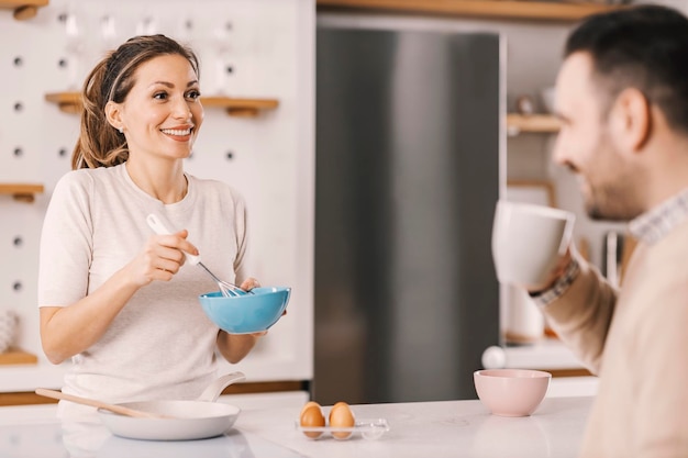 Mujer feliz haciendo un desayuno en casa y sonriendo a su novio