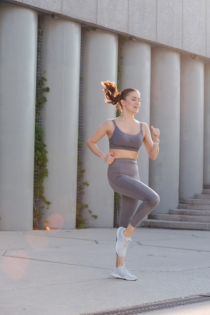 Mujer feliz haciendo ejercicio sobre un pavimento de hormigón corriendo sobre el terreno