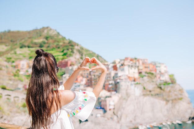 Mujer feliz haciendo con las manos en forma de corazón en el antiguo pueblo costero en el Parque Nacional Cinque Terre.