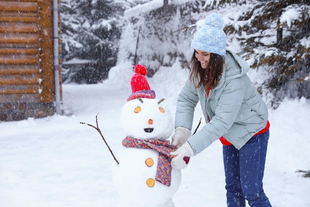 Mujer feliz haciendo muñeco de nieve al aire libre Vacaciones de invierno