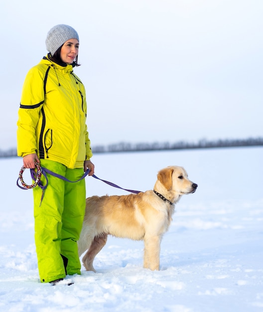 Mujer feliz con hermoso perro caminando en invierno