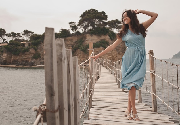 Foto mujer feliz joven en el puente cerca del mar