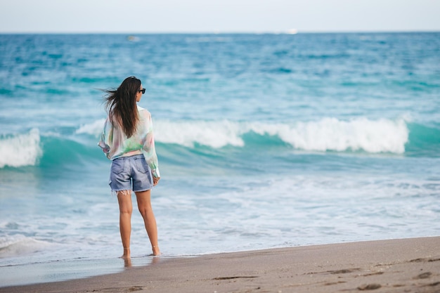 Mujer feliz joven que camina en la playa