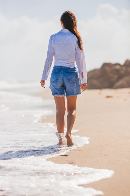 Mujer feliz joven que camina en la playa