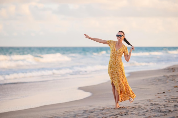 Mujer feliz joven que camina en la playa