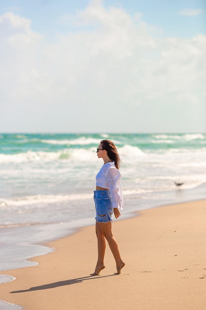 Mujer feliz joven que camina en la playa