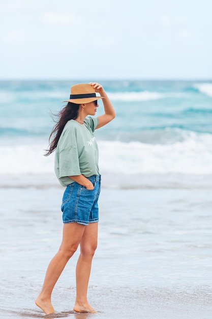 Mujer feliz joven que camina en la playa