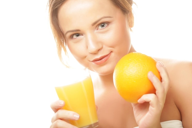 Mujer feliz joven que sostiene la naranja y el jugo