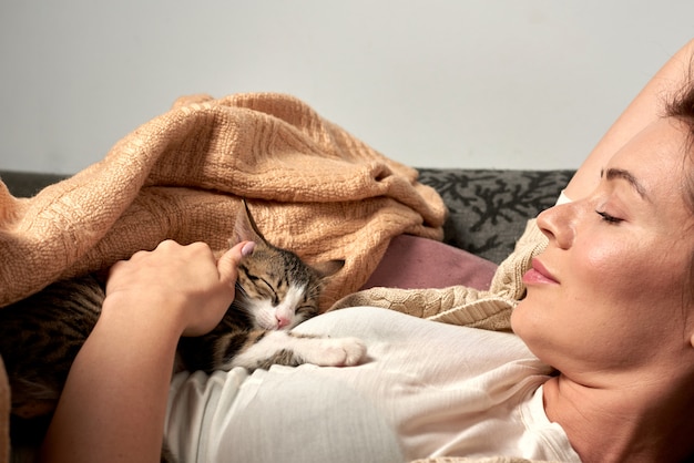 Mujer feliz jugando con el gato en el dormitorio