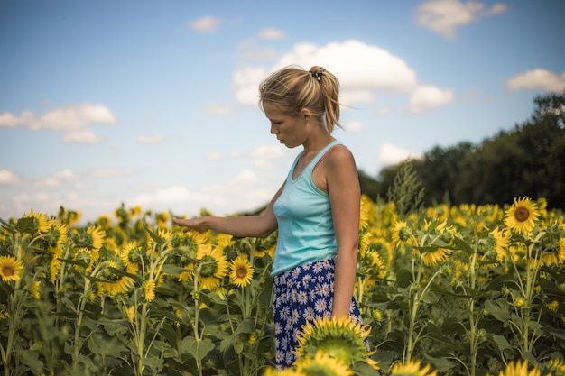 Mujer feliz jugando con girasol chica al aire libre divirtiéndose en el campo verde de la primavera