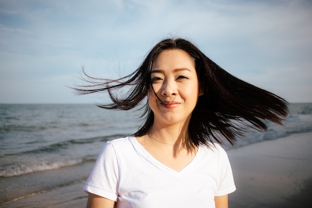 Mujer feliz y juguetona caminar en la playa y jugar con la cámara.