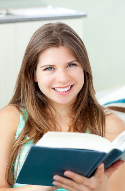 Mujer feliz leyendo un libro en la sala de estar