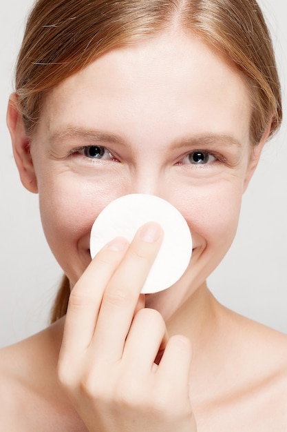 Mujer feliz limpiando su rostro con algodones