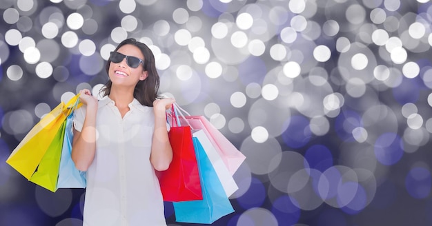 Mujer feliz llevando bolsas de compras sobre bokeh