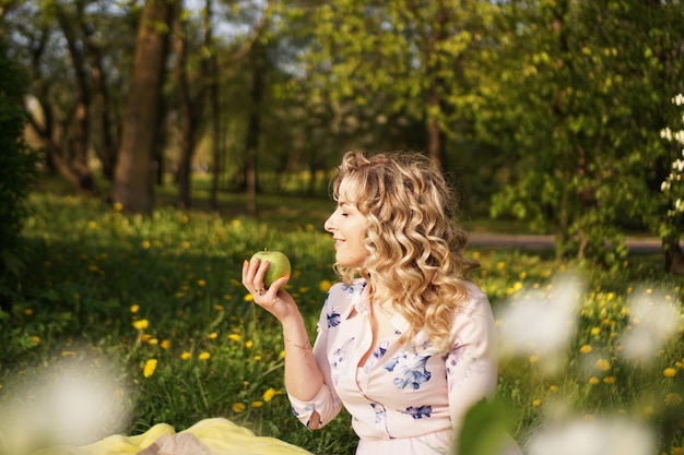 Mujer feliz con manzana en un picnic en el jardín de verano