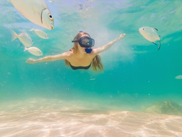 Mujer feliz con máscara de esnórquel bucear bajo el agua con peces tropicales en la piscina marina de arrecife de coral Estilo de vida de viaje deporte acuático aventura al aire libre clases de natación en vacaciones de verano en la playa