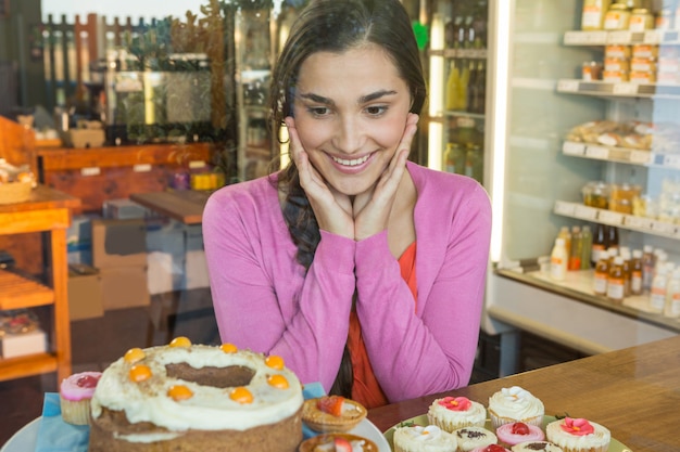 Foto mujer feliz mirando la exhibición de postres