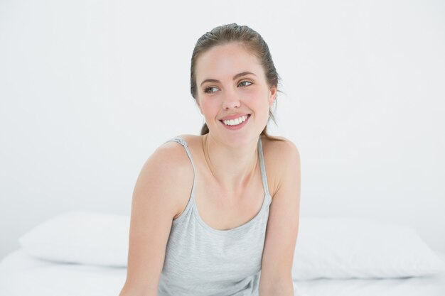 Mujer feliz mirando a otro lado en la cama