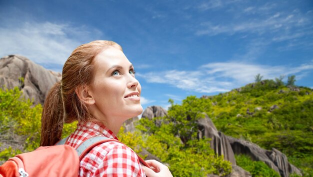 Foto mujer feliz con mochila sobre la isla de seychelles.