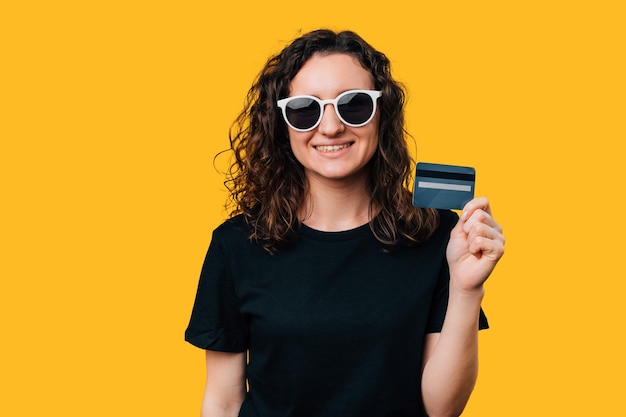 Mujer feliz mostrando una foto de estudio de tarjeta de crédito que ilustra la confianza financiera