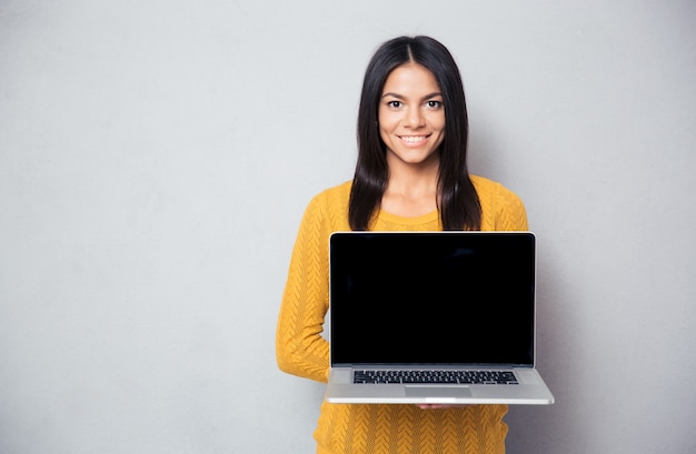 Mujer feliz mostrando la pantalla del portátil en blanco