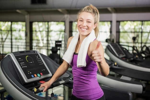 Mujer feliz mostrando sus pulgares para arriba en el gimnasio