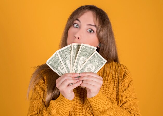 Mujer feliz con muchos billetes en sus manos sobre fondo amarillo