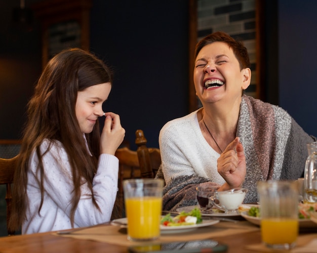 Foto mujer feliz y niña comiendo juntos