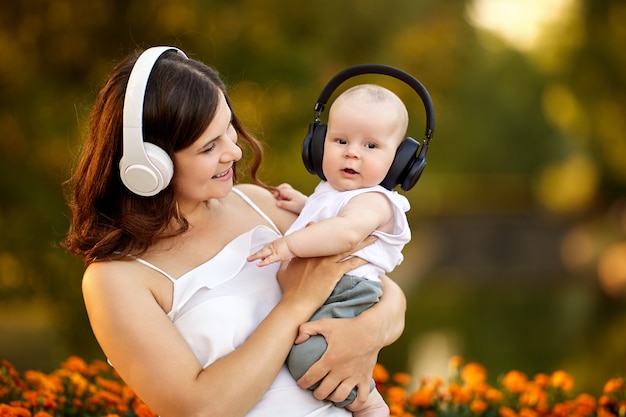 Mujer feliz con niño en auriculares inalámbricos camina al aire libre