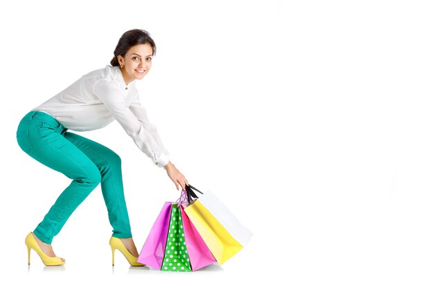 Mujer feliz en pantalón verde con bolsa de compras aislado sobre fondo blanco.