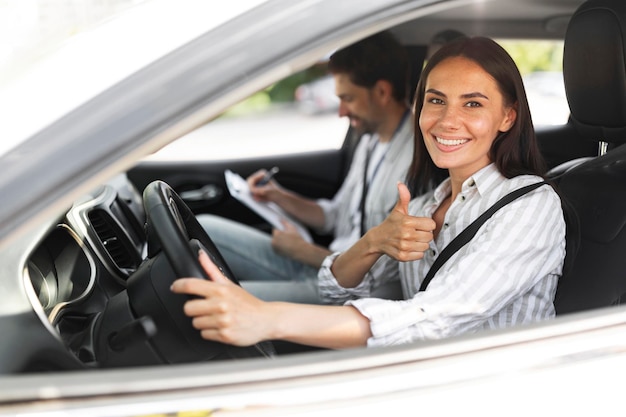 Foto mujer feliz pasando exámenes en la escuela de conducción mostrando el pulgar hacia arriba