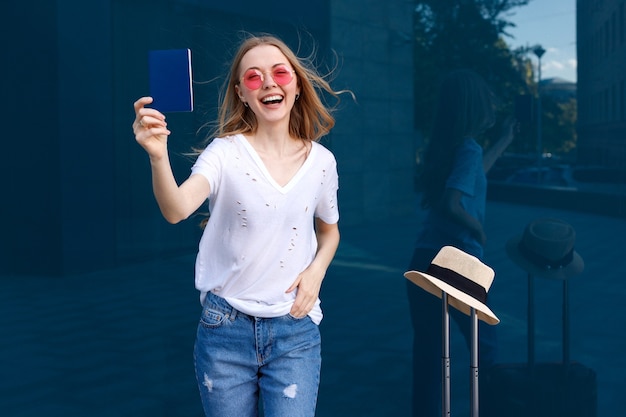 Mujer feliz con pasaporte y equipaje sobre un fondo azul.