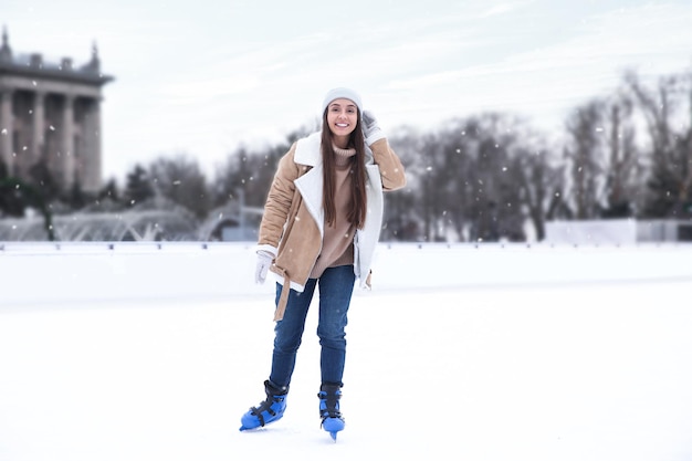 Mujer feliz patinando a lo largo de la pista de hielo al aire libre