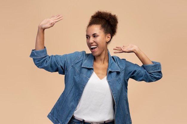 Mujer feliz con peinado afro brazos levantados bailando celebrando