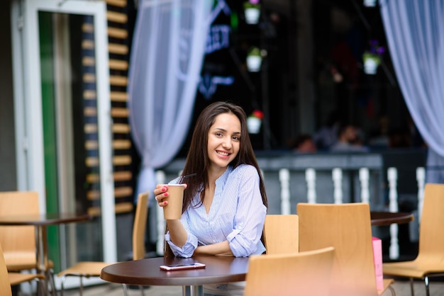 Mujer feliz pensativa bebiendo un batido en la calle